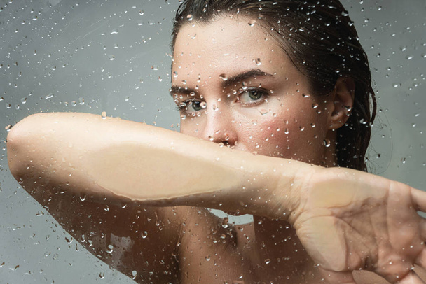 Portrait of beautiful and sensual woman captured through wet glass - Foto, Bild