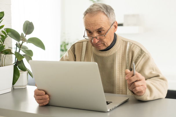 Busy smart mature professional man using laptop sitting. Middle aged older adult businessman, senior entrepreneur of mid age remote working or learning online typing on computer - Photo, Image