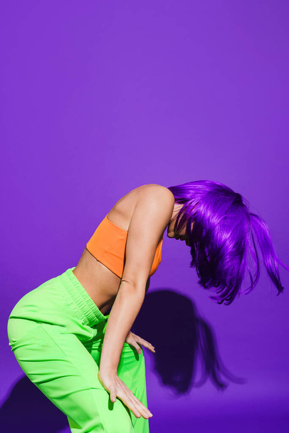 Carefree active woman dancer wearing colorful sportswear having fun against purple background - Foto, afbeelding