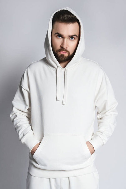 Handsome man wearing blank white hoodie and pants posing on gray background - 写真・画像