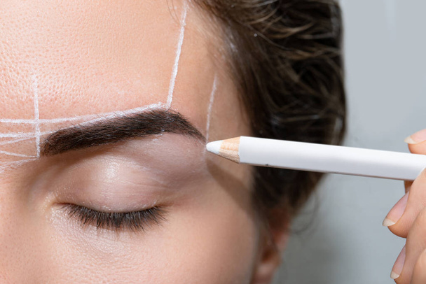 Young woman during professional eyebrow mapping procedure before permanent makeup - Valokuva, kuva