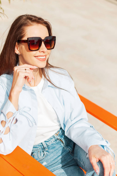 Beautiful happy sunny girl with a smile with vintage sunglasses sets, rest and enjoy on a spring warm day - Φωτογραφία, εικόνα
