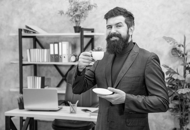 positive bearded business man drinking coffee in the office with copy space, morning. - Foto, Bild