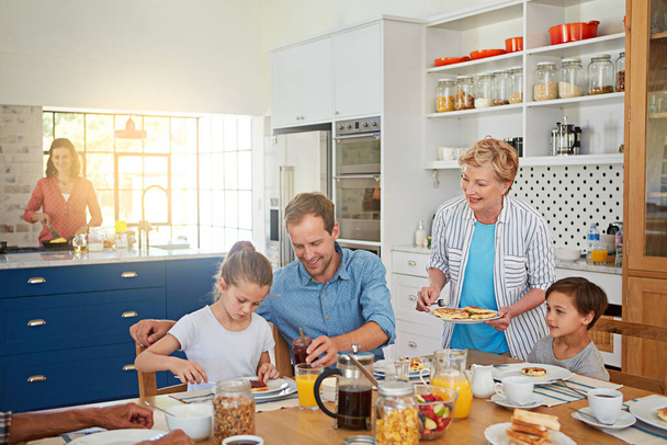 Its not breakfast without grandmas pancakes. a multi generational family enjoying breakfast together at home - Foto, imagen