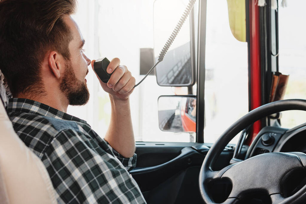 Male truck driver talking by CB radio system in his vehicle - Φωτογραφία, εικόνα