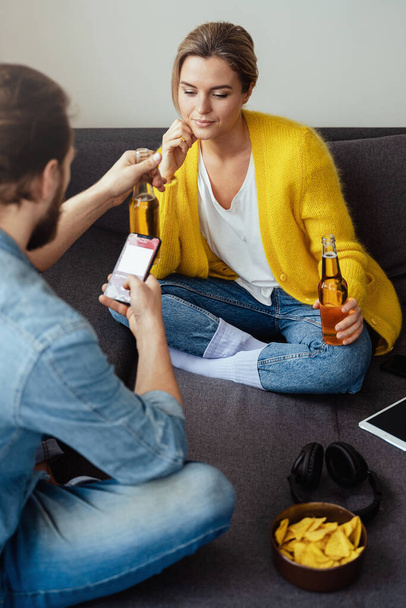 Young couple drinking beer and eating nachos chilling at home - Fotoğraf, Görsel