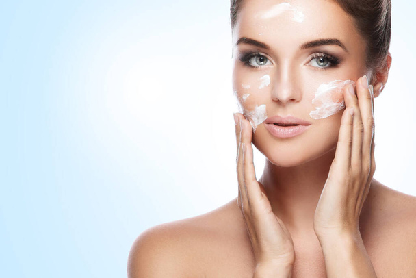 Young and beautiful woman applying moisturizing cream on her face - Valokuva, kuva