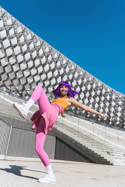 Carefree active woman dancer wearing colorful sportswear having fun on the street during sunny day - Foto, afbeelding