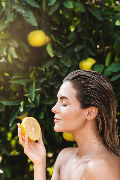 Szabadtéri portré gyönyörű nő sima bőr egy citrom gyümölcs a kezében - Fotó, kép
