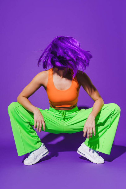 Portrait of woman wearing colorful sportswear against purple background - Photo, image