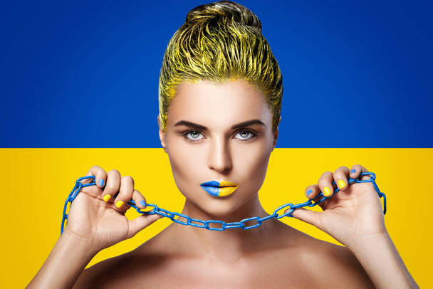 Strong and confident woman with yellow blue lipstick and Ukrainian flag on background - Foto, immagini