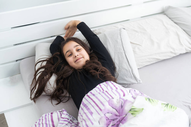 Teenager child girl daydreaming in bed, dreaming kids concept. Happy teen girl, positive and smiling emotions - 写真・画像