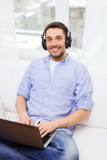smiling man with laptop and headphones at home - Foto, immagini