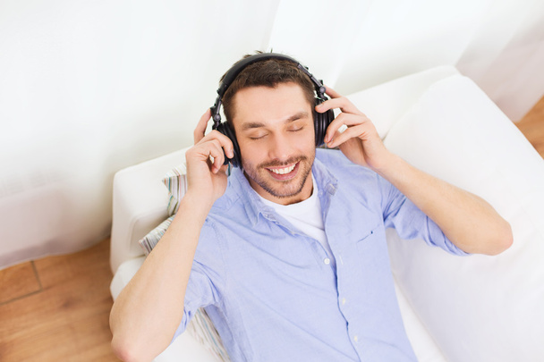 smiling young man in headphones at home - Фото, зображення