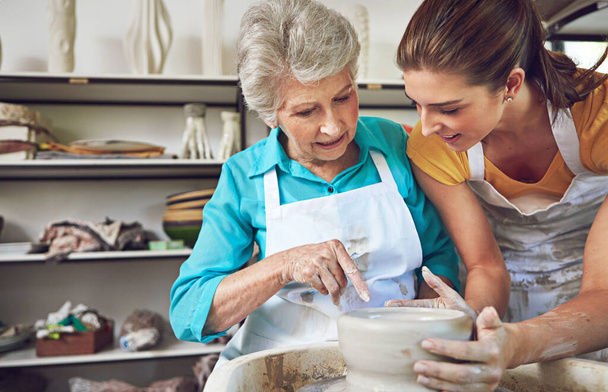 Átadja a fazekas tudását anyának. egy idősebb nő, aki kerámia edényt készít egy kerámia órán. - Fotó, kép