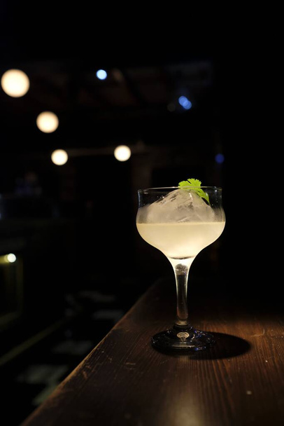 Pystysuora laukaus lasillinen cocktail puinen pöytä bokeh valot taustalla - Valokuva, kuva