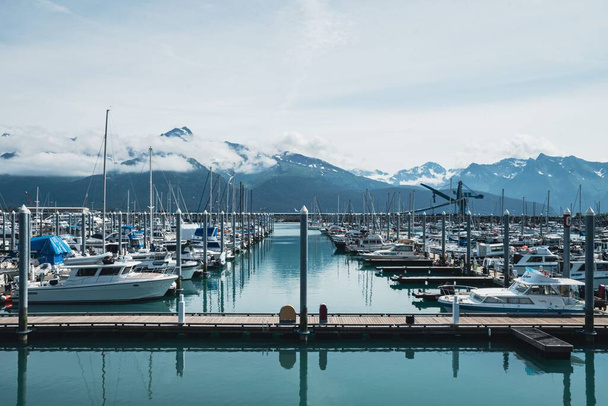 a beautiful day at a calm boat harbor with snow-capped mountains in the background - 写真・画像