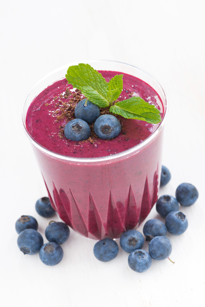 blueberry milkshake in a glass on white table, close-up - Zdjęcie, obraz