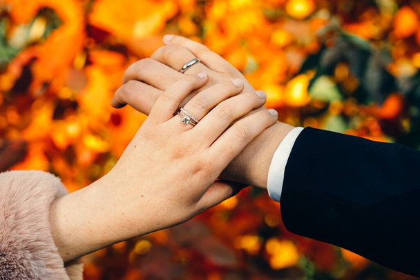 A closeup of a bride and groom hands wearing wedding rings - Fotó, kép