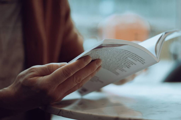 A closeup shot of a person holding open a book while reading - Fotoğraf, Görsel