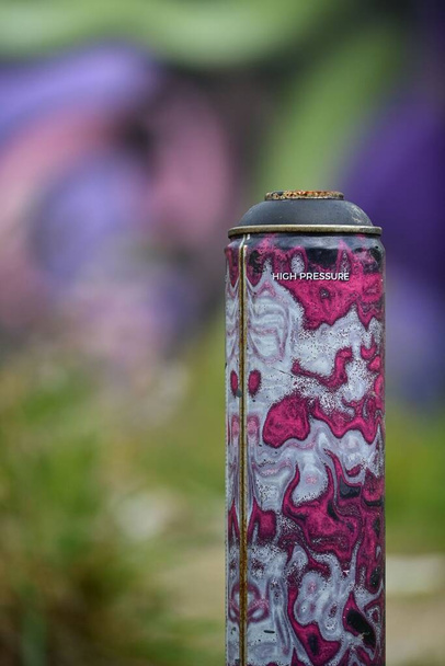 A closeup shot of a metal can with a graffiti wall in the background - Photo, image