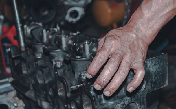 The auto mechanic repairing the engine of a car on the blurred background - Foto, imagen