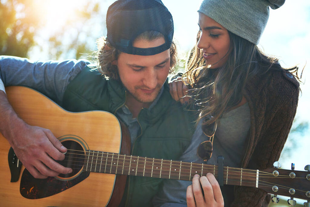 Zaciska odpowiedni akord w moim sercu. młody człowiek gra swoją dziewczynę piosenkę na gitarze - Zdjęcie, obraz