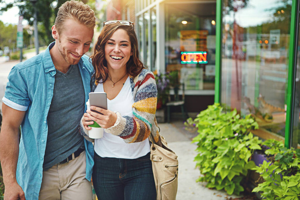 Explorer la ville par internet. un jeune couple heureux utilisant un smartphone ensemble tout en passant la journée au centre-ville - Photo, image