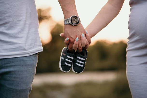 A couple holding each other's hand with baby shoes - Foto, Imagem