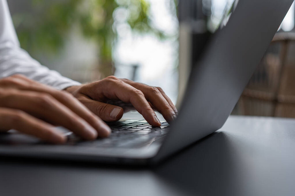 Businessman using laptop on desk, closeup fingers typing on keyboard, blurred background. Concept of online shopping, website and communication - Fotó, kép