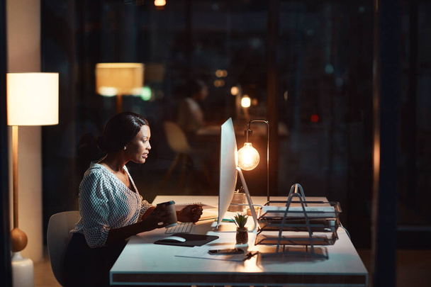 Lo hace por el éxito. una joven empresaria que usa una computadora durante una noche en el trabajo - Foto, Imagen