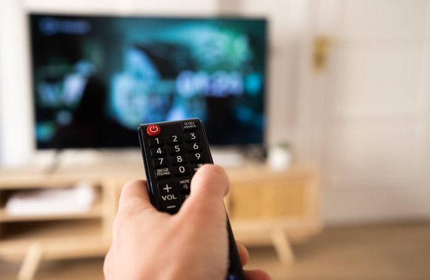 hand with remote control for tv set - Φωτογραφία, εικόνα