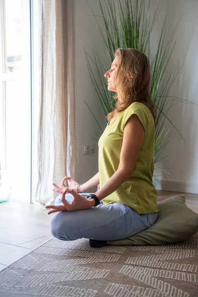 женщина медитирует дома в гостиной - Фото, изображение