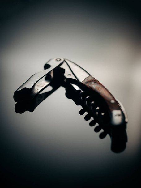 A vertical closeup shot of a metal corkscrew and its reflection on an isolated background - Фото, изображение