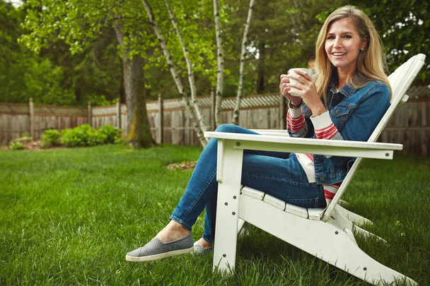 Coffee and some fresh air. a mature woman sitting in her backyard - Foto, imagen