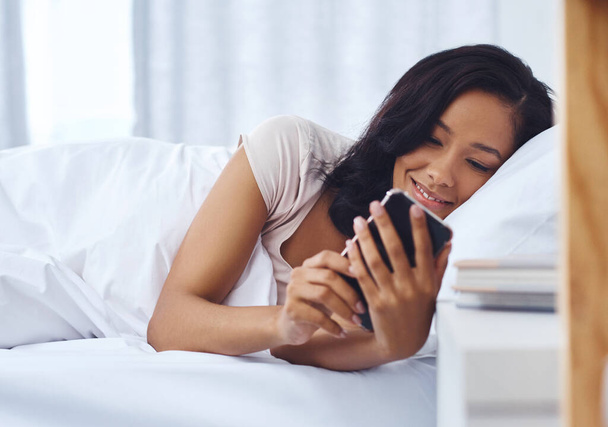 Τι όμορφο μήνυμα για να ξυπνάς. μια νεαρή γυναίκα ξυπνάει το πρωί και χρησιμοποιεί το τηλέφωνό της στο κρεβάτι - Φωτογραφία, εικόνα