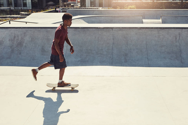 Always stay in motion. Full length shot of a young man doing tricks on his skateboard at a skate park - Foto, imagen