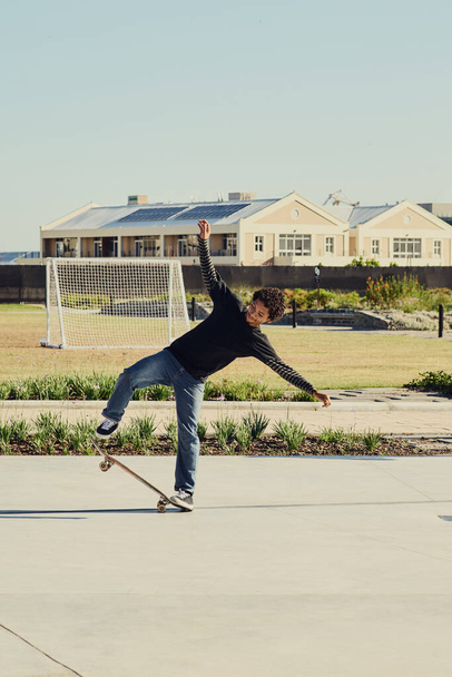 Balance is everything in life. Full length shot of a young man doing tricks on his skateboard at a skate park - 写真・画像
