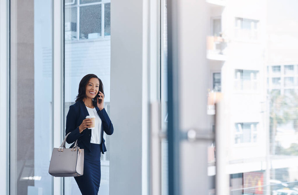 Business moves to the pace that she does. a young businesswoman talking on a cellphone in an office - 写真・画像