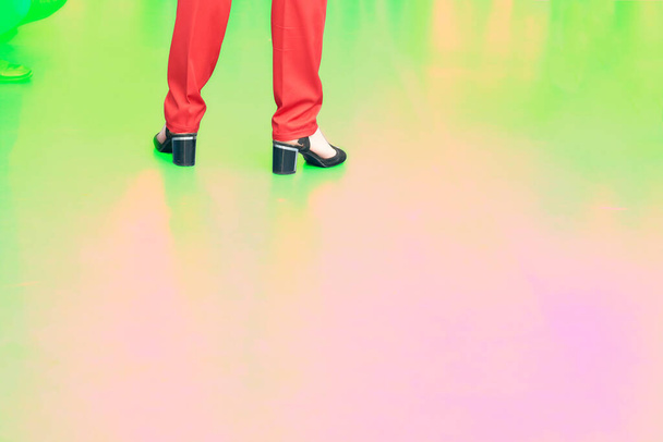 Woman legs in red trousers and black sandals shoes on a yellow pink green - Φωτογραφία, εικόνα