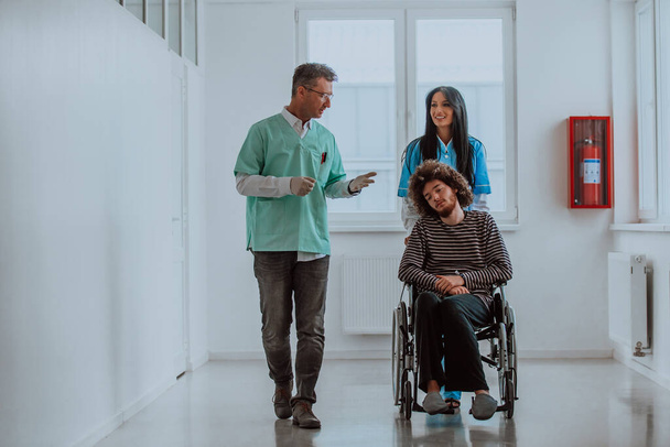 Lekarz i pielęgniarka rozmawiający o zdrowiu pacjenta podczas gdy pacjent, który jest na wózku inwalidzkim, jest obecny obok nich - Zdjęcie, obraz