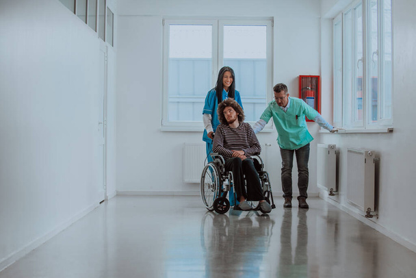 Lekarz i pielęgniarka rozmawiający o zdrowiu pacjenta podczas gdy pacjent, który jest na wózku inwalidzkim, jest obecny obok nich - Zdjęcie, obraz