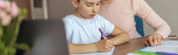 Ritratto di bella madre che aiuta il piccolo figlio adolescente con i compiti a casa in copybook. Esercizio di scrittura. - Foto, immagini