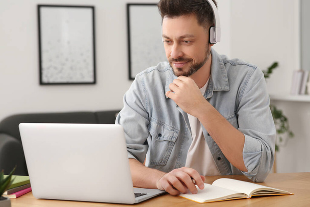 Man in headphones studying on laptop at home. Online translation course - Fotoğraf, Görsel