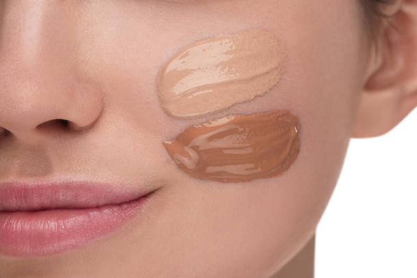 Teenage girl with swatches of foundation on face against white background, closeup - Photo, image