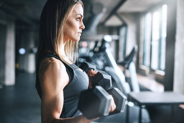 Unterschätzen Sie niemals Ihre eigene Stärke. eine junge Frau trainiert mit Gewichten in einem Fitnessstudio - Foto, Bild