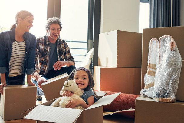 How did she get in the box again. Portrait of a cheerful loving family packing out boxes together in their new home during the day - 写真・画像