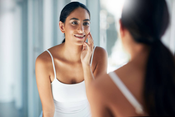As minhas peles estão cheias e vibrantes. uma jovem mulher atraente inspecionando sua pele na frente do espelho do banheiro - Foto, Imagem