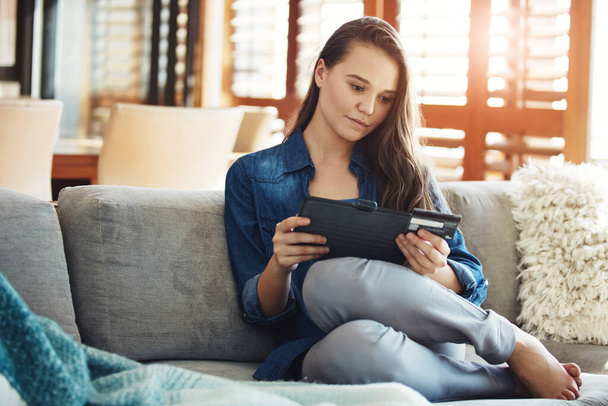 Pankkitoiminta verkossa. houkutteleva nuori nainen käyttää hänen tabletti tehdä ostoksia verkossa, kun rentoudut sohvalla kotona - Valokuva, kuva