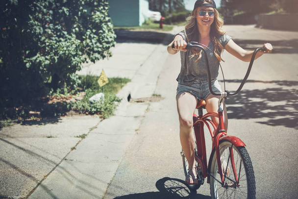 Havalı arabaların varken yürümene gerek yok. Dışarıda bisiklet süren çekici bir genç kadın. - Fotoğraf, Görsel